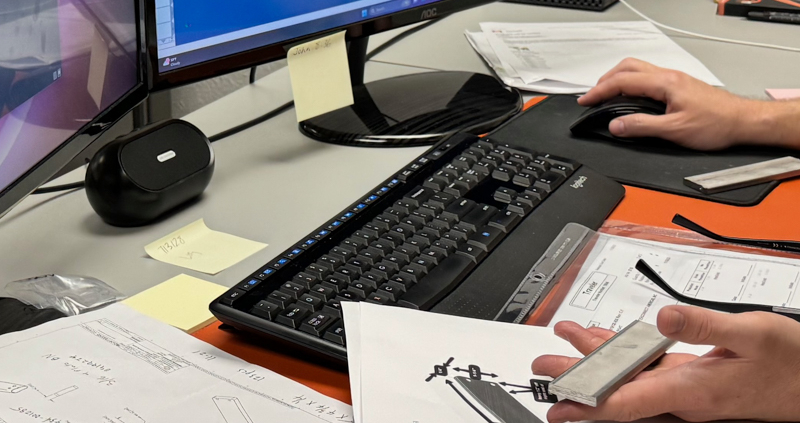 An engineer works intently at a computer station, using CAD software to transform concepts into detailed engineering blueprints. The focus is on the screen displaying complex diagrams, illustrating the precision and expertise involved in the engineering process.